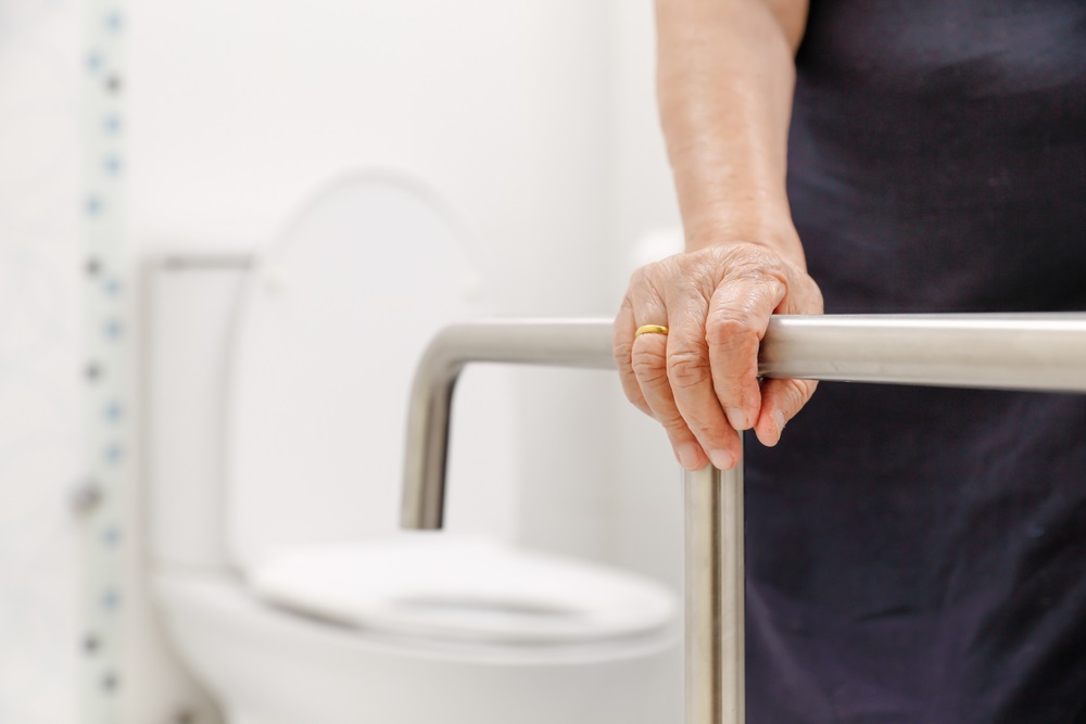 elderly woman holding on handrail in bathroom