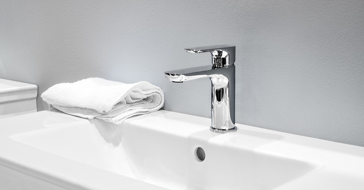 faucet mixer and white towel on a white sink in a beautiful gray bathroom