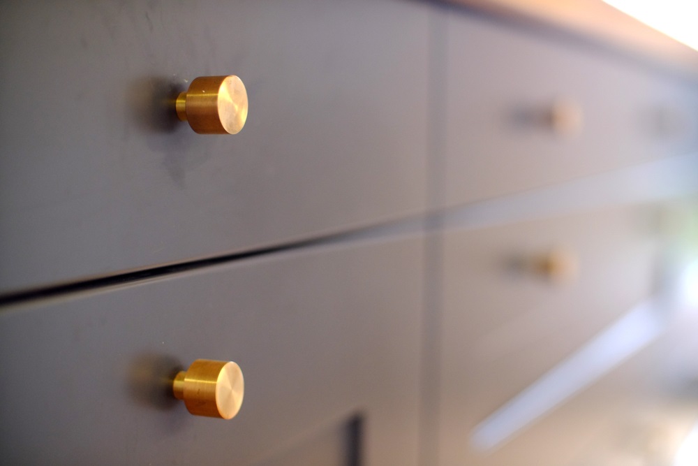 small brass knobs on grey kitchen drawers