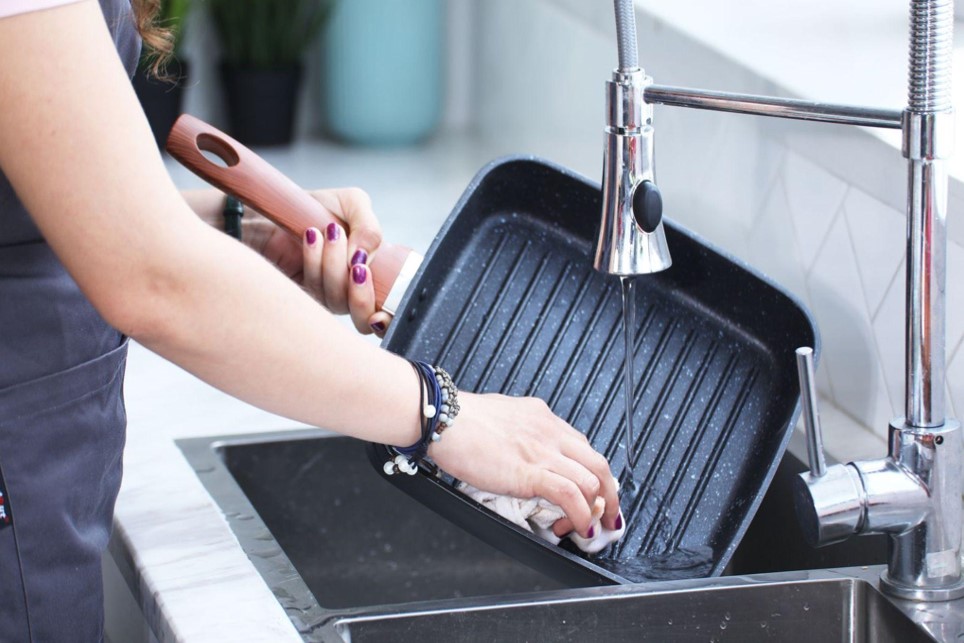 women washing pan in kitchen
